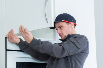 handyman fixing the cupboard in the kitchen