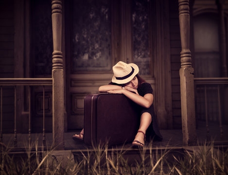 Woman sitting on threshold of old house.