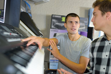 Fototapeta na wymiar happy young man trying a piano at music store