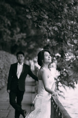 Fototapeta na wymiar Chinese Wedding couple standing in the alley of green leaves
