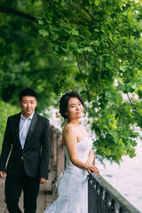 Chinese Wedding couple standing in the alley of green leaves