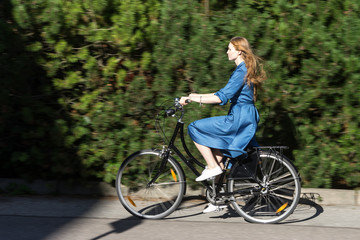 Beautiful young woman and vintage bicycle, summer. Red hair girl riding the old black retro bike outside in the park. Having fun in the city