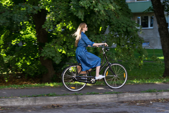 Beautiful young woman and vintage bicycle, summer. Red hair girl riding the old black retro bike outside in the park. Having fun in the city