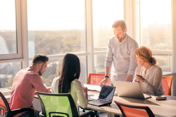 Business people working on laptop computer and listening to their boss in board room in office....