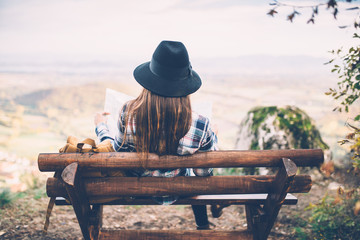 Hipster woman sitting on bench and looking for direction on viewpoint