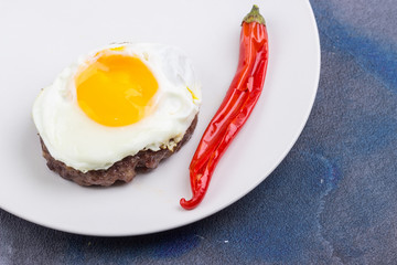 Beefsteak with fried egg and chili pepper