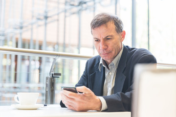Businessman looking at the smart phone in a cafe