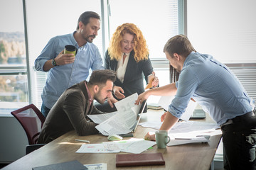 Obraz premium Business people looking through documents all together and happy smiling while working in team in board room in office interior. Teamwork concept.