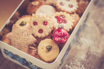 Blechdose mit Weihnachtsplätzchen und Lebkuchen, auf rustikalem Holz
