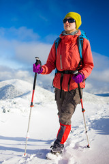 Girl with backpack walking on snow in the mountains.