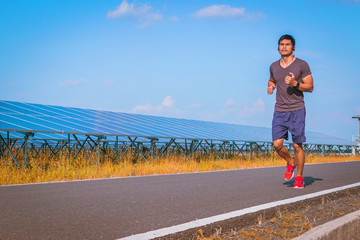 Fototapeta premium handsome man running on road with solar power plant in morning ;Healthy lifestyle with green energy 