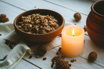 Christmas porridge with candles on white wooden background