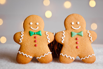 Two gingerbread man with candy standing on a blurred background. Christmas card