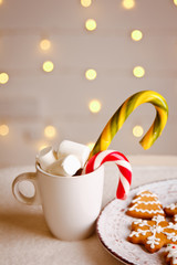 Beautiful Christmas background with gingerbread cookies on white plate with Cup of marshmallows and candy