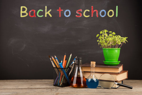 Back to school concept - books on the desk over the blackboard