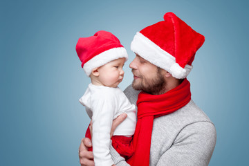 Father with baby boy wearing Santa hats celebrating Christmas