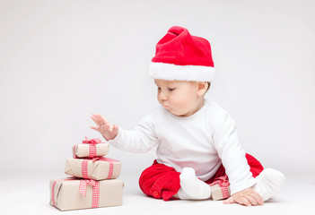 Adorable baby wearing a Santa hat opening Christmas presents