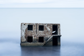 Liepaja beach bunker. Brick house, soft water, waves and rocks. Abandoned military ruins facilities in a stormy sea. Barracks building in the Baltic sea.  Liepaja, Latvia, Europe.