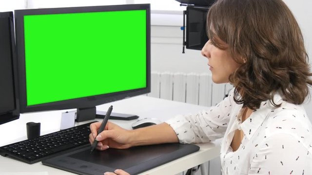 Young female designer using graphics tablet while working with computer