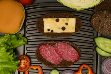 two sandwiches on the grill and ingredients around