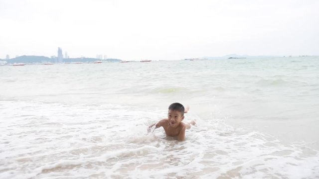 Slow motion of young Asian Thai boy playing on the sand beach
