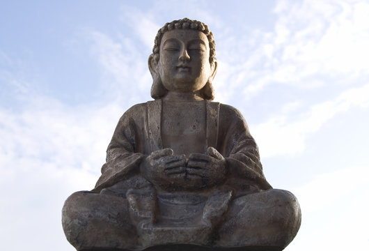 Sitting Buddha image on blue sky background.