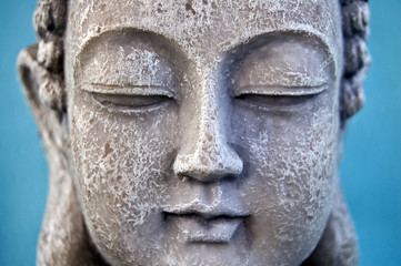 Fototapeta na wymiar Buddha face on blue background. Close up.
