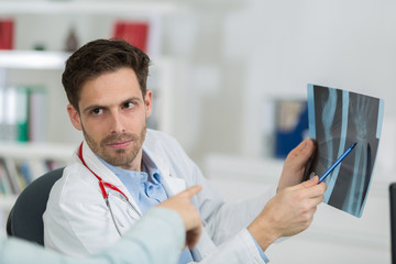 male doctor with patient looking at x-ray at office