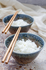 Cooked rice in ceramic bowl and chopsticks, vertical