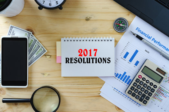 Top view conceptual image of working table. Words 2017 RESOLUTIONS on notepad.