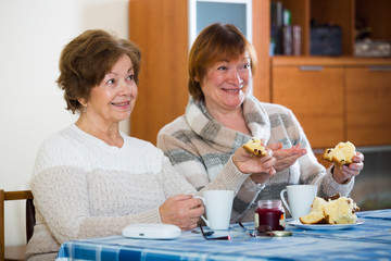 Female pensioners watching TV channel and drinking tea