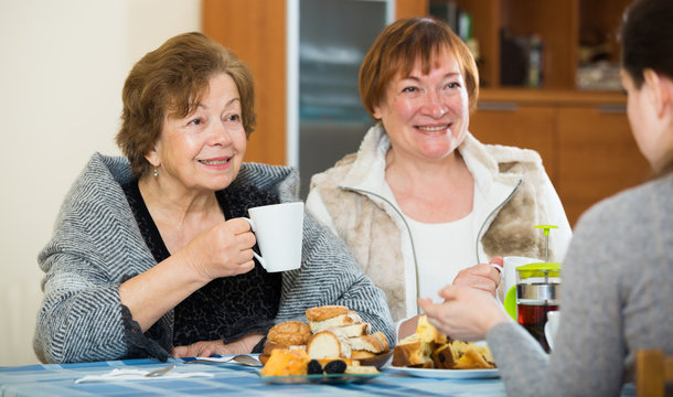 Senior women talking with girl while tea drinking