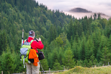 Photographer or traveler takes photos with digital camera in carpathian forest.