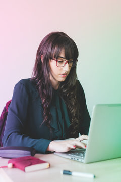 Young beautiful caucasian businesswoman sitting on a desk, using computer - technology, working, business concept