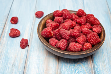 Raspberry in bowl on blue  wooden  background. Selective focus. Organic food.