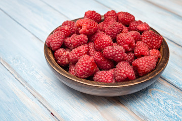 Raspberry in bowl on blue  wooden  background. Selective focus. Organic food.