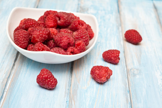 Raspberry in bowl on blue  wooden  background. Selective focus. Organic food.