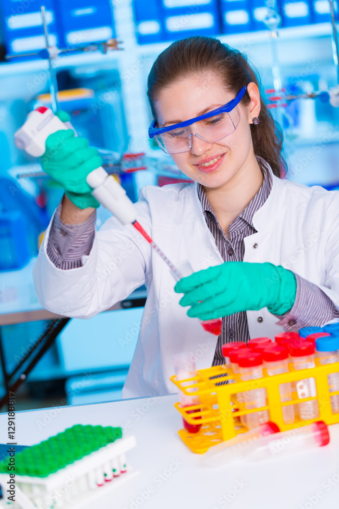 Wall mural A young chemist holding test tube with liquid during chemical experiment.