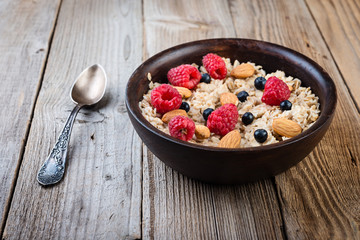  Homemade oatmeal with berries and nuts on wooden background. Healthy breakfast