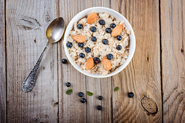  Homemade oatmeal with berries and nuts on wooden background. Healthy breakfast