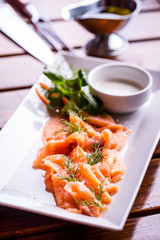 Salmon. Sliced smoked salmon with dressing and herb decoration.Serving sliced salmon in a restaurant or hotel.