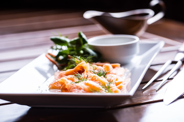Salmon. Sliced smoked salmon with dressing and herb decoration.Serving sliced salmon in a restaurant or hotel.