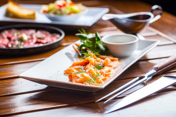 Salmon. Sliced smoked salmon with dressing and herb decoration.Serving sliced salmon in a restaurant or hotel.