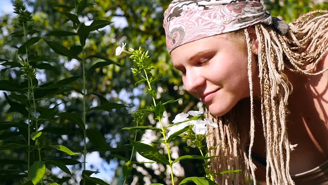 Girl with dreadlocked smelling a flower. HD