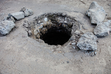 Broken manhole without cover in asphalt surface © rootstocks