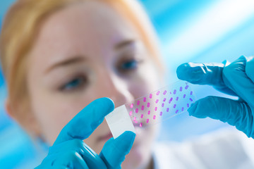 Woman science Assistant in laboratory with microscope slide  of cancer stem cells.