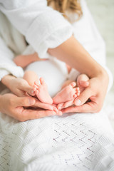 Father and Mother Holding Newborn Kid. Child feet Closeup 