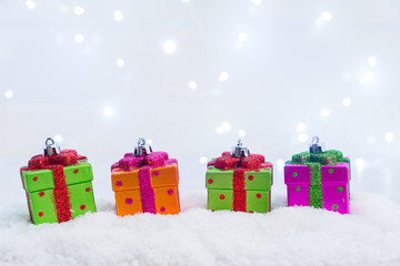 Row of Christmas presents in snow with lights bokeh in background