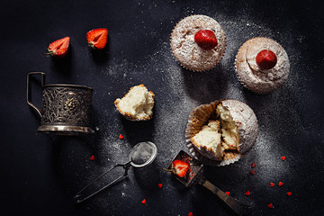 Christmas cupcakes with strawberries and powdered sugar on  black background. Top view. Festive winter food backdrop.