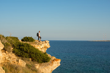 Hiker with backpack standing on the rocky cliff